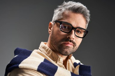 Gözlüklü şık bir adam şık bir arkaplana karşı şık bir elbise içinde poz verir..