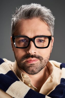 Yakışıklı bir adam şık bir stüdyo ortamında gözlük ve şık bir kıyafet giyer..