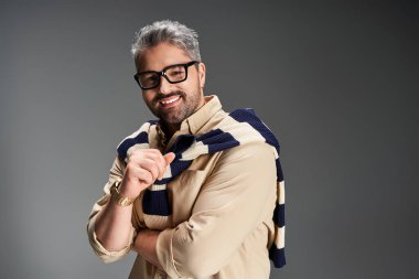 Zarif bir adam sofistike bir stüdyoda gülümserken şık kıyafetini gösterir..