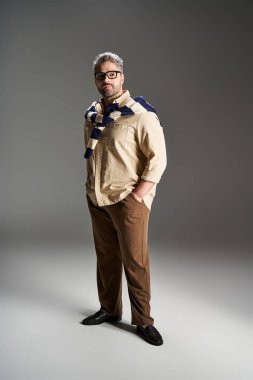 Gözlüklü şık bir adam şık bir elbise içinde, kendine güvenle poz verir. Moda yeteneği yayar..