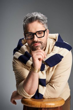 Yakışıklı adam şık kıyafetler içinde, stüdyo ortamında moda anlayışı sergiliyor..