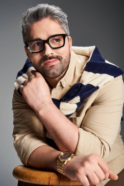 Gözlüklü şık bir adam modaya uygun kıyafetlerini ve çekiciliğini sergiliyor..