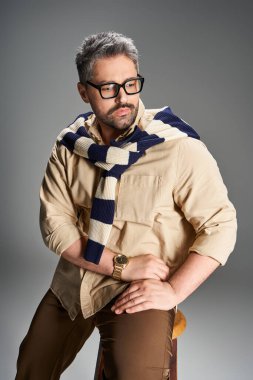 Gözlüklü yakışıklı bir adam kendine güvenerek şık bir poz verir, zarafet saçar..