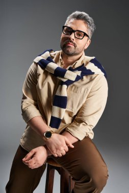 Gözlük takan yakışıklı bir adam şık bir kıyafetle rahatça poz verir..