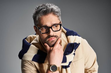 Yakışıklı bir adam şık bir elbise içinde düşünceli bir şekilde poz veriyor, harmanlama tarzı ve zarafeti zahmetsizce.