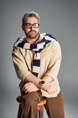 Gözlüklü şık bir adam stüdyoda sofistike bir yeteneği olan şık bir kıyafet sergiliyor..