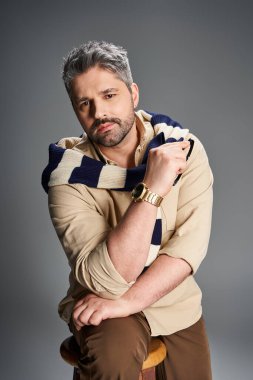 Yakışıklı adam şık bir stüdyoda modaya uygun kıyafetler sergiliyor, zahmetsiz karizma ve tarz yayıyor..