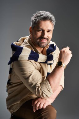 Tüylü çekici bir adam modern bir stüdyo ortamında moda tarzını sergiliyor..