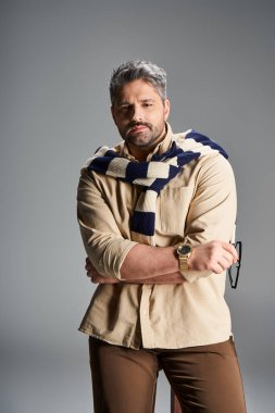 Kendine güveni olan bir adam şık bir kıyafet içinde, stüdyo ortamında modaya uygun bir görünüm sergiliyor..