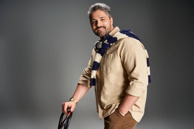 Kendine güvenen bir adam moda stüdyosunda poz verirken şık bir kıyafet sergiliyor..