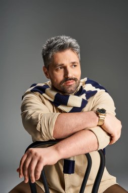 Şık giyinmiş yakışıklı bir adam tarafsız bir arkaplanda kendine güvenir..