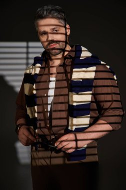 Tüylü şık bir adam, modaya uygun bir kıyafetin içinde, modern tarzın somut bir şekilde poz verir..