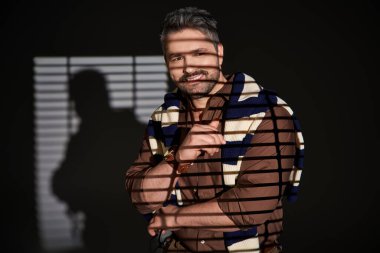 Şık bir adam stüdyonun sanatsal ışığında rahatça poz verir..