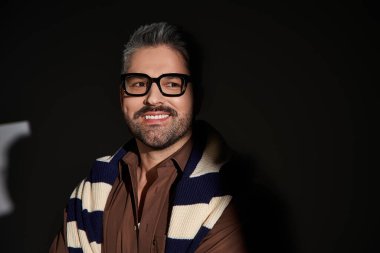 Yakışıklı bir adam, kendine güvenen şık bir elbiseyle stüdyoda modern moda yeteneğini sergiliyor..