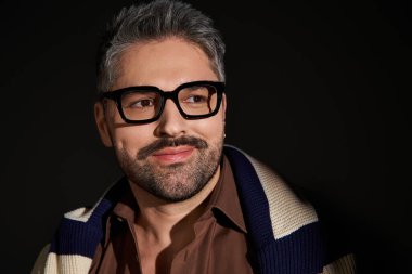 Yakışıklı bir adam şık bir kıyafetle, gözlüklü, şık bir şekilde poz verir..