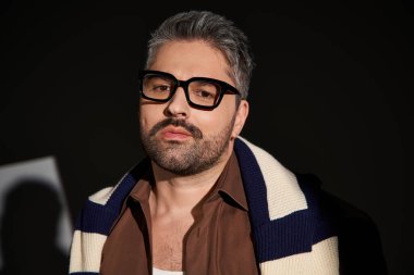 Yakışıklı bir adam şık bir kıyafet içinde poz veriyor. Stüdyoda kendine güveni ve tarzı var..