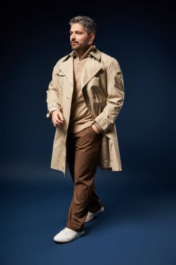 Tarz sahibi bir adam, modaya uygun bir kıyafetle karanlık bir stüdyo arkaplanına karşı poz verir..