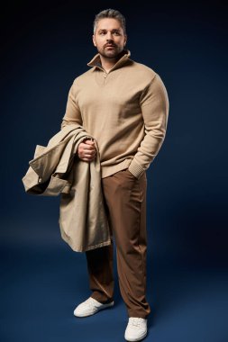 Tüylü yakışıklı bir adam şık bir elbise içinde kendinden emin bir şekilde duruyor..