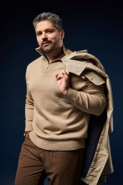 Tüylü şık bir adam stüdyoda moda kıyafetlerini ve duruşunu sergiliyor..