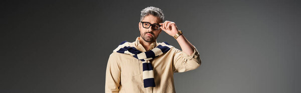 A fashionable man showcases a trendy outfit while posing confidently in a chic studio, banner