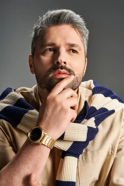 Bakımlı sakallı şık bir adam modern bir stüdyo ortamında özenle poz veriyor..