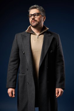 Gözlüklü yakışıklı adam modaya uygun ve şık bir kıyafet içinde kendinden emin bir şekilde poz veriyor..