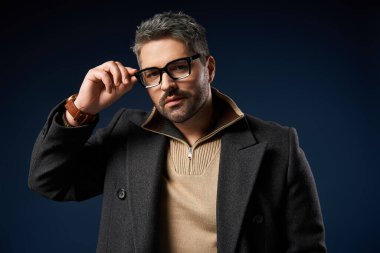 Gözlüklü yakışıklı adam şık bir stüdyo arkaplanına karşı şık bir kıyafete güveniyor..