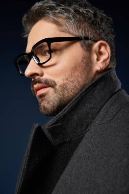 Şık gözlüklü yakışıklı bir adam, bir stüdyoda şık ve şık bir kıyafet giyiyor..