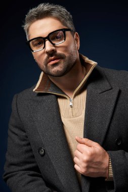 Yakışıklı bir adam modaya uygun bir kıyafetle kendine güvenerek poz verir, şık tarzını ön plana çıkarır..