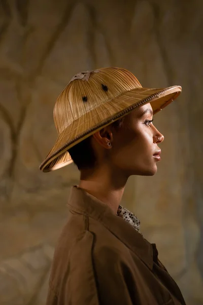 Vista lateral del arqueólogo en sombrero de safari y chaqueta marrón en el desierto - foto de stock