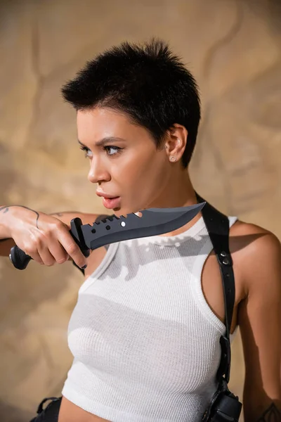 Tattooed and sexy archaeologist with short hair holding sharp knife — Stock Photo