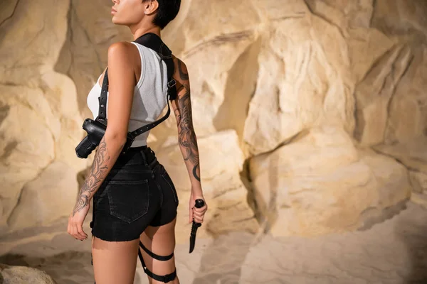 Partial view of tattooed and sexy archaeologist with short hair holding sharp knife — Stock Photo