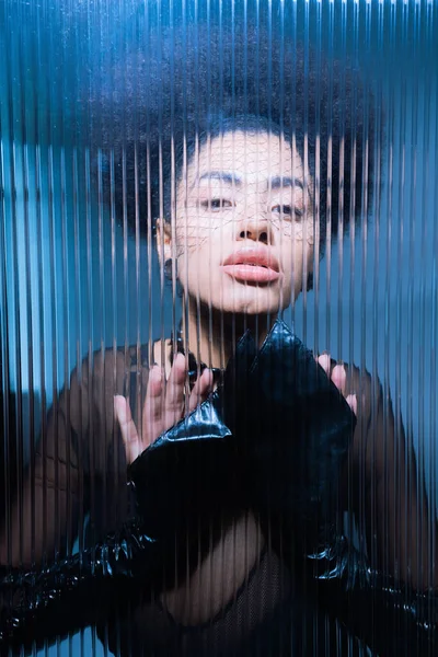 Молодая африканская американка в черной вуали смотрит в камеру сквозь потрепанное стекло — стоковое фото