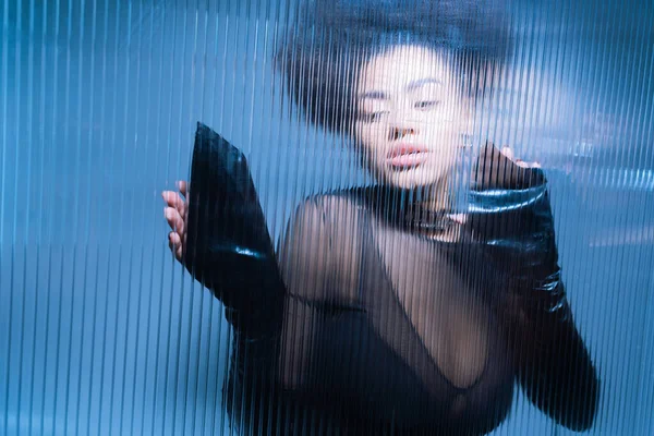 Modelo americano Africano bonita em roupa sexy preta olhando para longe através de vidro babados — Fotografia de Stock