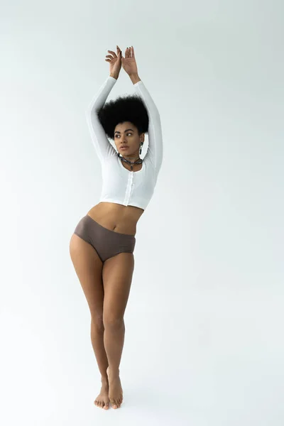 Full length of barefoot african american woman posing in long sleeve shirt and panties on white — Stock Photo