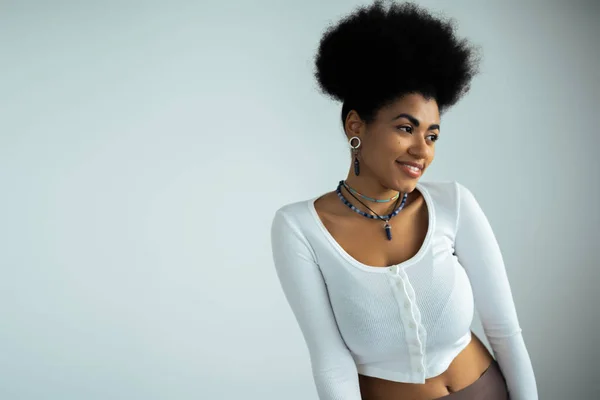 Счастливая африканская американка в рубашке с длинным рукавом, улыбающаяся на белом фоне — стоковое фото