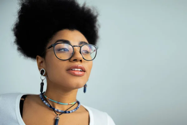 Retrato de mujer afroamericana soñadora en gafas y accesorios aislados en gris - foto de stock