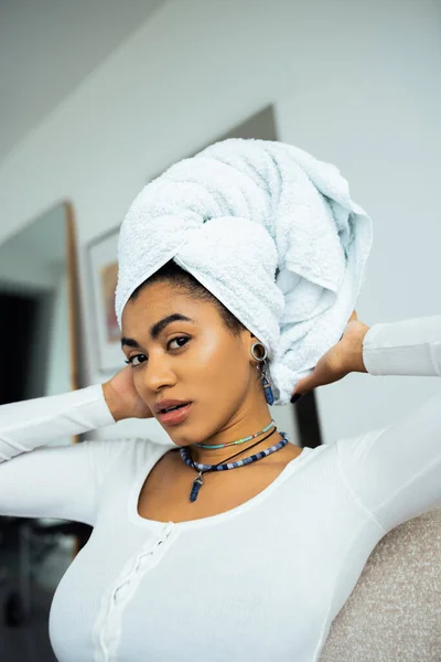 Hübsche Afroamerikanerin richtet Handtuch auf dem Kopf ein, während sie in die Kamera schaut — Stockfoto