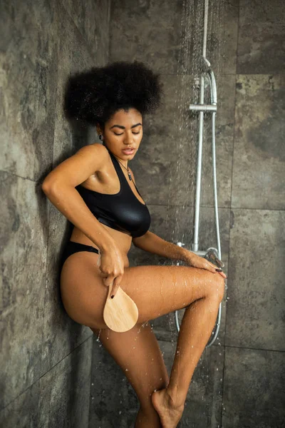 Africano americano mulher massageando corpo com escova no chuveiro em casa — Fotografia de Stock