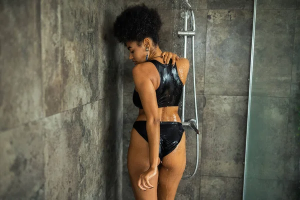 Vue latérale de la jeune femme afro-américaine prenant une douche à la maison — Photo de stock