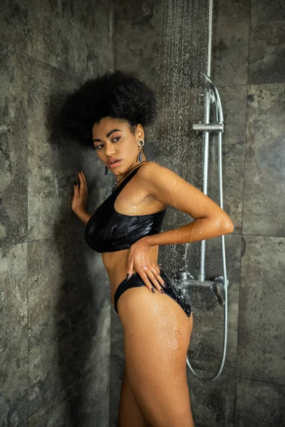 Donna afroamericana in crop top e mutandine in piedi sotto l'acqua nella doccia — Foto stock