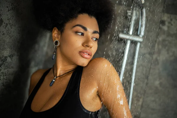 Jeune femme afro-américaine frisée en haut de la culture regardant loin tout en prenant une douche — Photo de stock