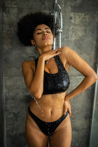 Jolie femme afro-américaine regardant la caméra tout en prenant une douche à la maison — Photo de stock