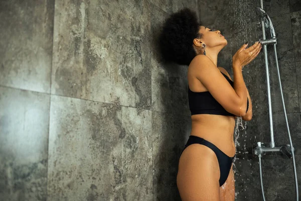 Vista laterale della donna afroamericana bruna che si fa la doccia a casa — Foto stock