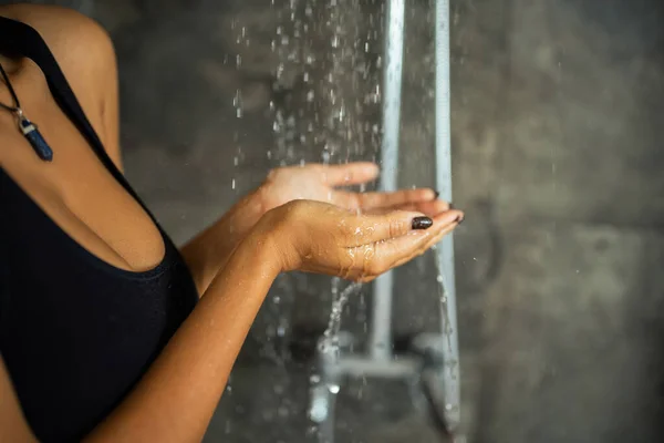 Vista recortada de la mujer afroamericana en la parte superior de la cosecha de la mano bajo el agua en la ducha - foto de stock