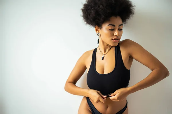 Sexy african american woman touching crop top near wall at home — Stock Photo