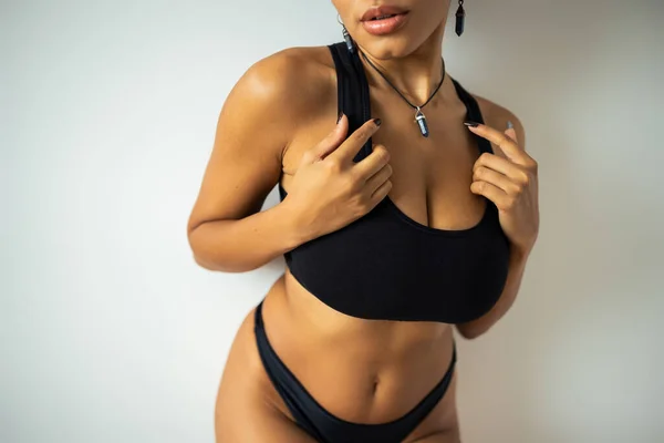 Ausgeschnittene Ansicht einer sexy afrikanisch-amerikanischen Frau in schwarzem Crop Top und Höschen, die in der Nähe der Wand steht — Stockfoto