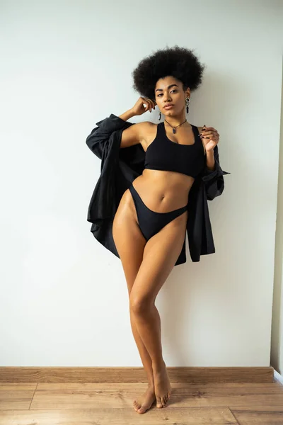 Sexy africana americana mujer en camisa y ropa interior mirando a la cámara en casa - foto de stock