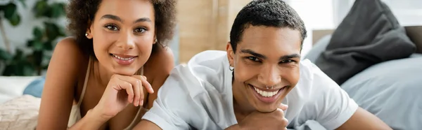 Pleased african american couple looking at camera in bedroom, banner — Stock Photo