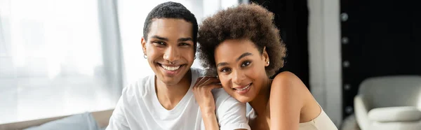 Brunette african american woman hugging happy boyfriend and smiling at camera, banner — Stock Photo